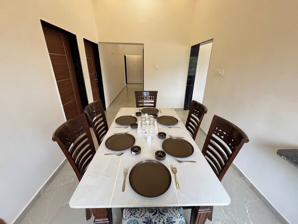 A dining area with a rectangular table set for four, surrounded by wooden chairs.