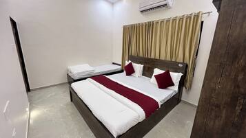 A hotel room with two beds, a wooden headboard, beige curtains, and a ceiling light.