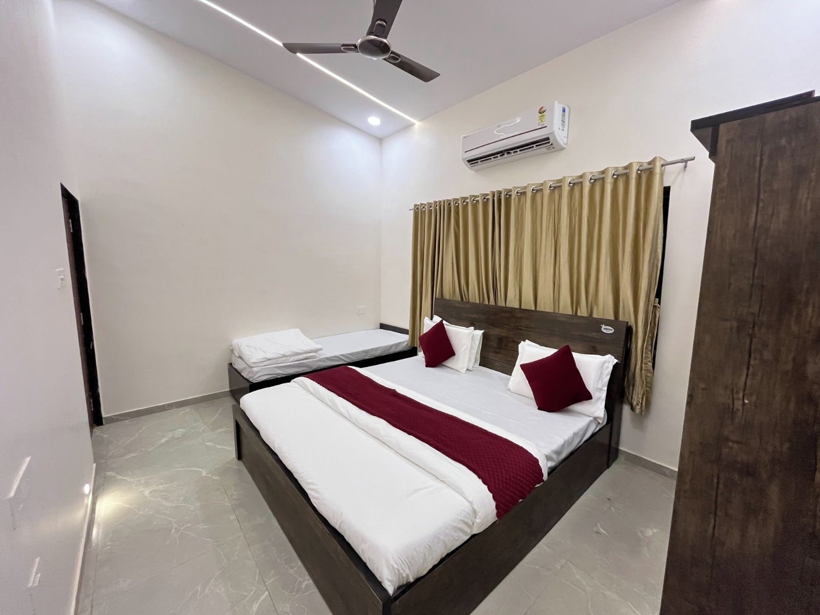Una habitación de hotel con una cama, un ventilador de techo, un equipo de aire acondicionado y un armario.