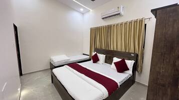 Una habitación de hotel con una cama, un ventilador de techo, un equipo de aire acondicionado y un armario.