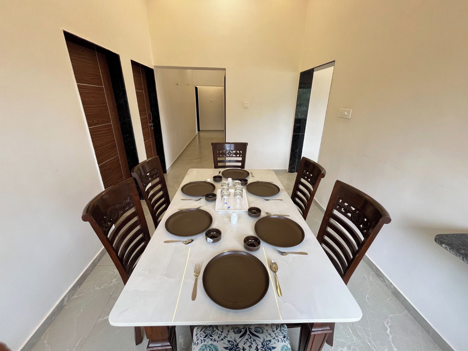 A dining area with a rectangular table set for four, surrounded by wooden chairs.