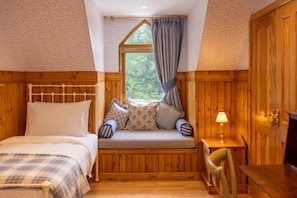 A cozy room with a bed, a bench with cushions, a small table with a lamp, and wooden walls. - The Log Cabin at Rokeby Manor (Invergarry)