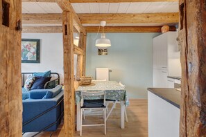 A cozy room with a wooden ceiling, a dining table with a floral tablecloth, a blue sofa, and a white chair. - Apartment 'Lucia - Duplex Climatisé' with Mountain View, Wi-Fi and Air Conditioning (Obernai)