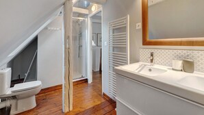 Un baño con lavamanos blanco, espejo y ducha.