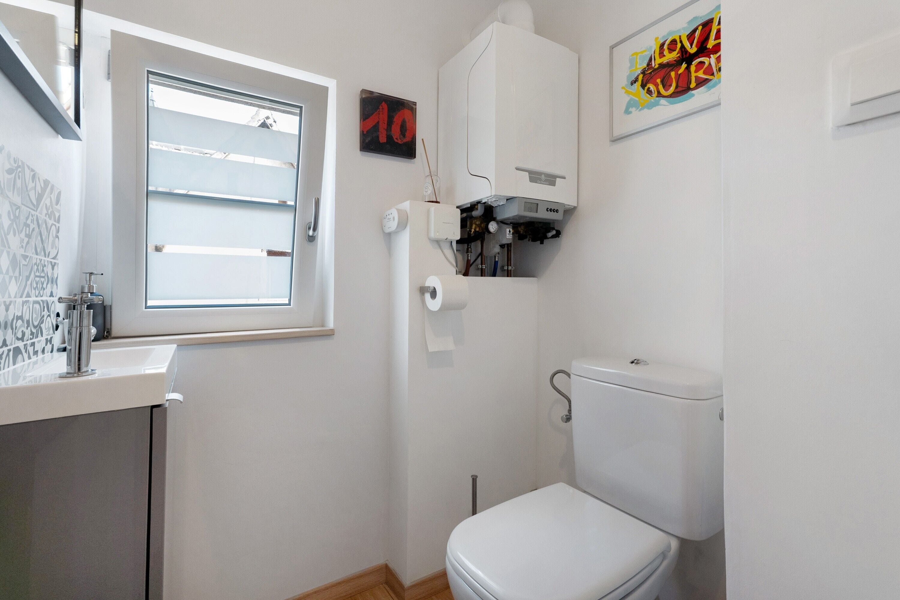 Une petite salle de bain propre, équipée de toilettes, d’une fenêtre et d’une douche.