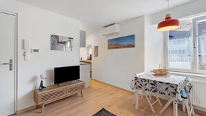 Una sala moderna con televisor, mueble bajo para equipo multimedia de madera y un comedor con mesa y sillas.