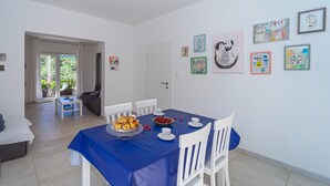 Ein Essbereich mit blauem Tischlein, weißen Stühlen und einer Obstschale.