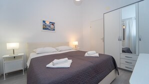 A hotel room with a bed, two bedside tables with lamps, a wardrobe, and a painting on the wall.