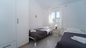 Ein Schlafzimmer mit zwei Betten, einem Nachttisch, einem Kleiderschrank und einem Fenster mit Vorhängen.