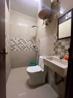 A compact bathroom with a toilet, shower, and sink. - Smart Stay Malviya Nagar (New Delhi)