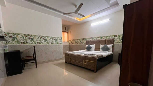 Habitación de hotel con cama, una silla, escritorio y ventilador de techo.