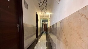 Un pasillo con suelo de mármol, una puerta de madera y un techo con diseño.