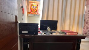 Un escritorio de madera con dos monitores, un teclado, una pequeña estatua y un libro rojo.