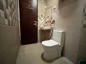 A small bathroom with a toilet, sink, and mirror. - Smart Stay Malviya Nagar (New Delhi)