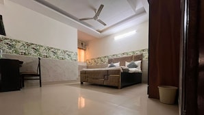 Un dormitorio con cama, una silla, ventilador de techo y piso de baldosas.