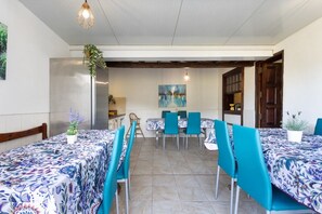 A dining area with two tables, blue chairs, and a painting on the wall.