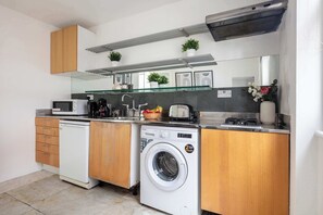 Eine kompakte Küche mit Holzausstattung, einer integrierten Waschmaschine, einer Mikrowelle und einem Toaster.