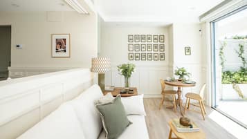 Uma sala de estar moderna com um sofá, uma mesa de jantar com cadeiras, um abajur e quadros nas paredes.