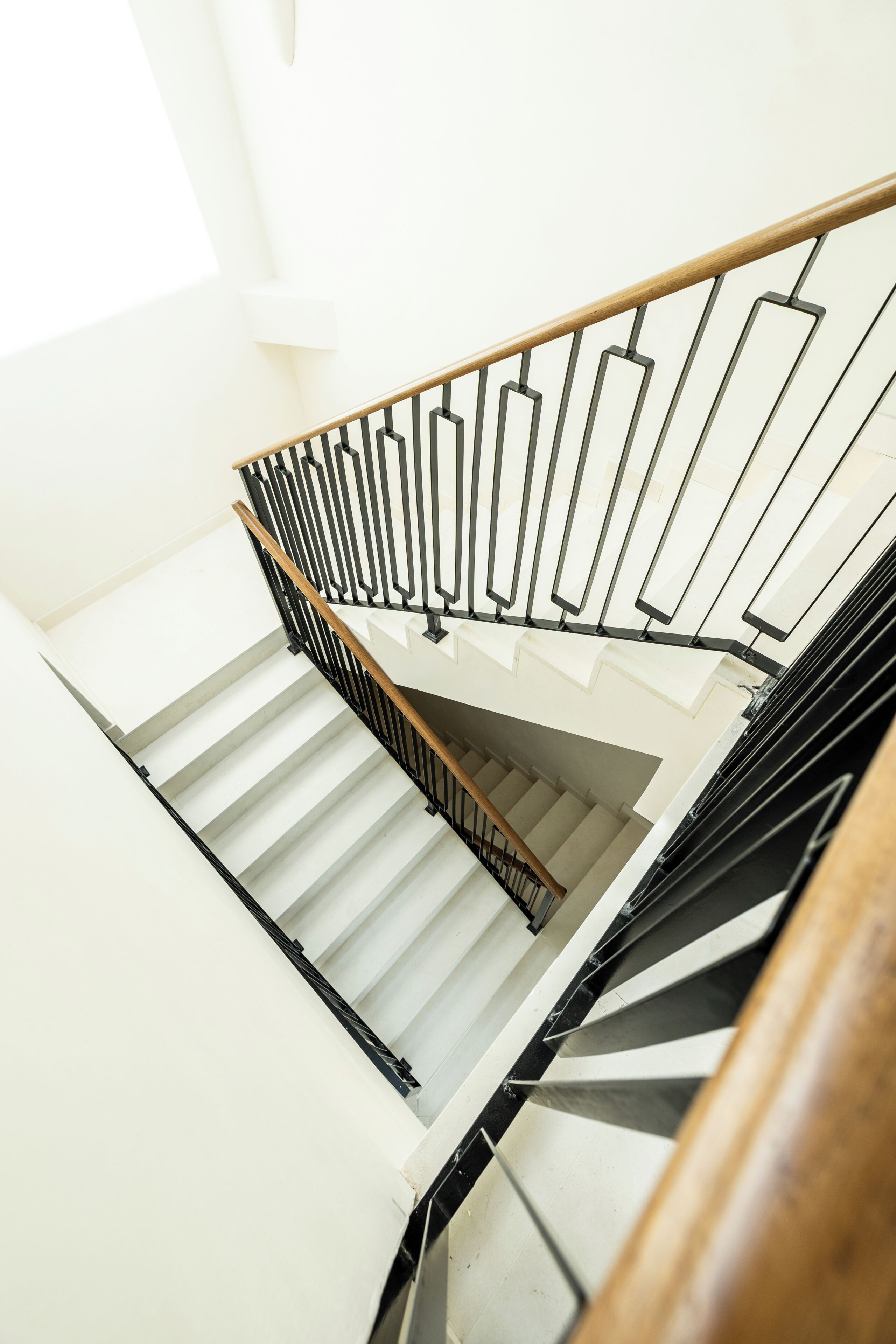 Una escalera con barandilla de madera y balaustradas de metal.