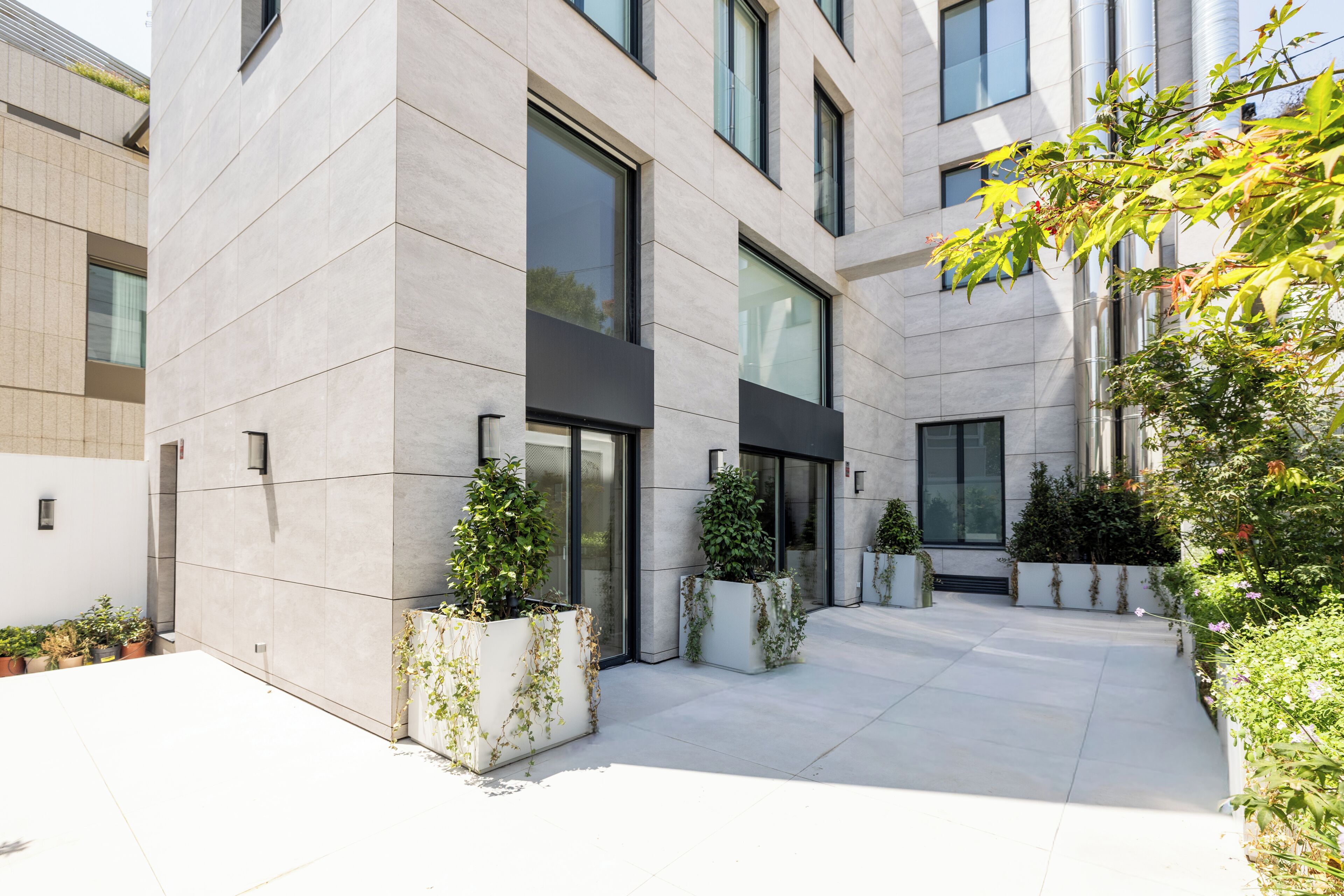 A modern building with large windows, a courtyard with potted plants, and a clean, tiled floor.