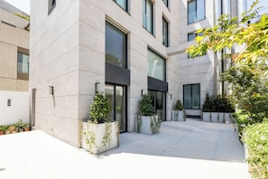 Un edificio moderno con ventanas amplias, un patio con plantas en macetas y un suelo limpio de baldosas.