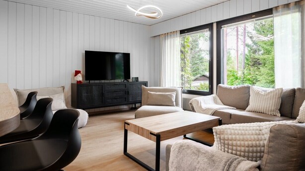 A modern living room with a flat-screen TV, a black entertainment unit, a beige sofa, and a wooden coffee table. - Teddy`s Hideout, Private Sauna By Lapland Host (Rovaniemi)