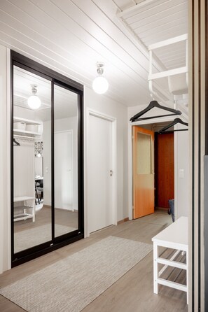 A hallway with a sliding glass door leading to a room, a coat rack, and a small table with a chair. - Teddy`s Hideout, Private Sauna By Lapland Host (Rovaniemi)