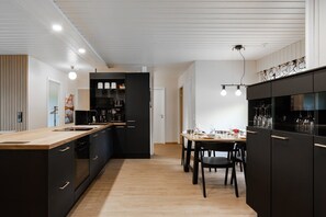 A modern kitchen with dark cabinetry, a wooden countertop, and a dining area with a table set for two. - Teddy`s Hideout, Private Sauna By Lapland Host (Rovaniemi)