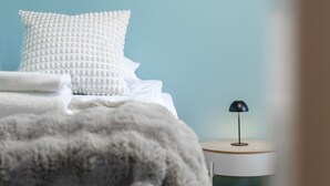 A bedroom with a bed, pillows, a blanket, a bedside table with a lamp, and a nightstand. - Teddy`s Hideout, Private Sauna By Lapland Host (Rovaniemi)