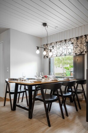 A dining area with a long wooden table, black chairs, and pendant lighting. - Teddy`s Hideout, Private Sauna By Lapland Host (Rovaniemi)