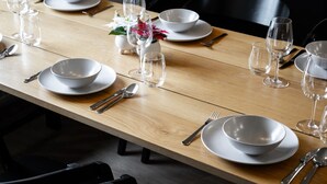 A dining table set with white plates, bowls, and cutlery, with empty wine glasses and a small vase with flowers. - Teddy`s Hideout, Private Sauna By Lapland Host (Rovaniemi)