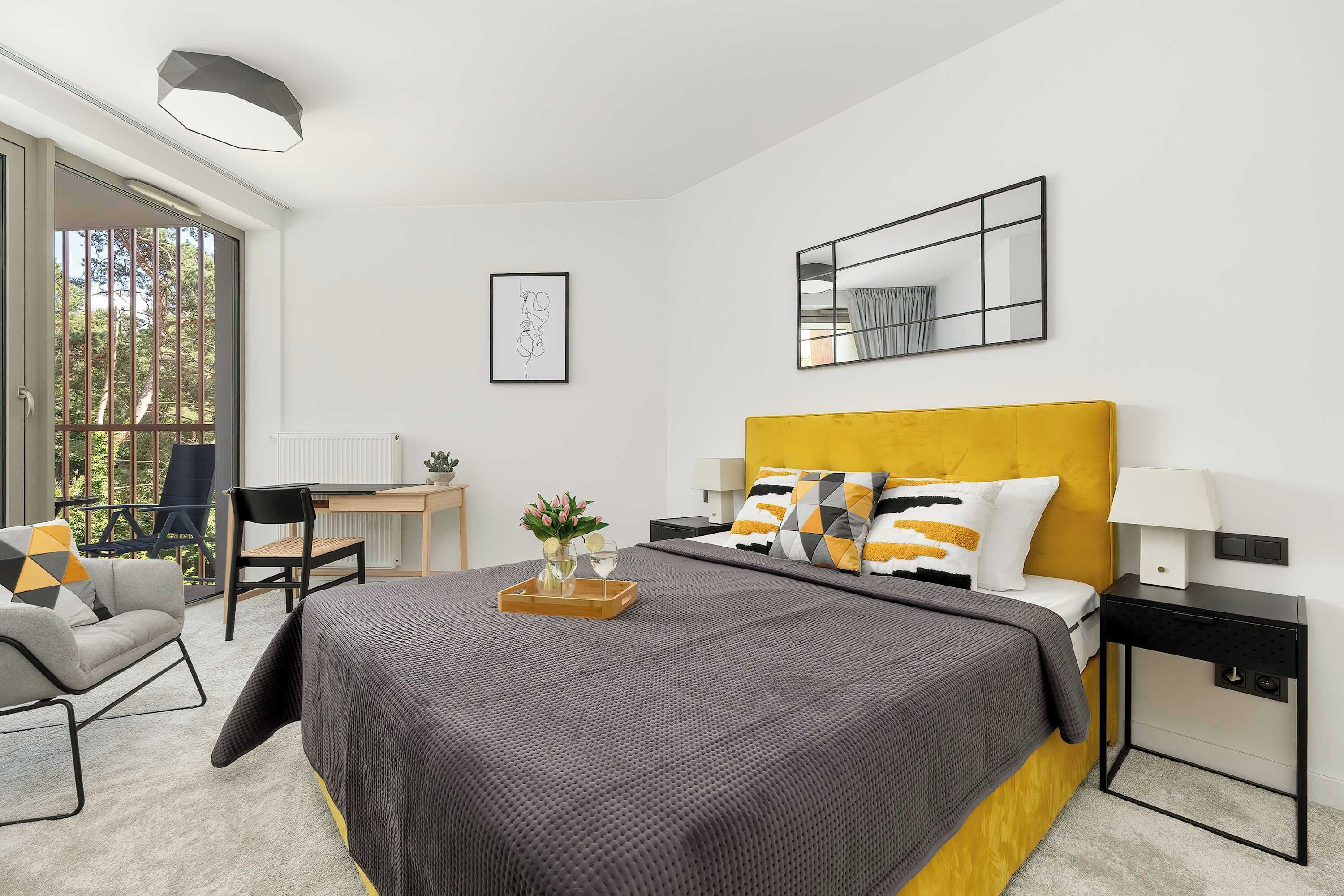 A modern bedroom with a large bed, bedside tables, a desk, and a chair.