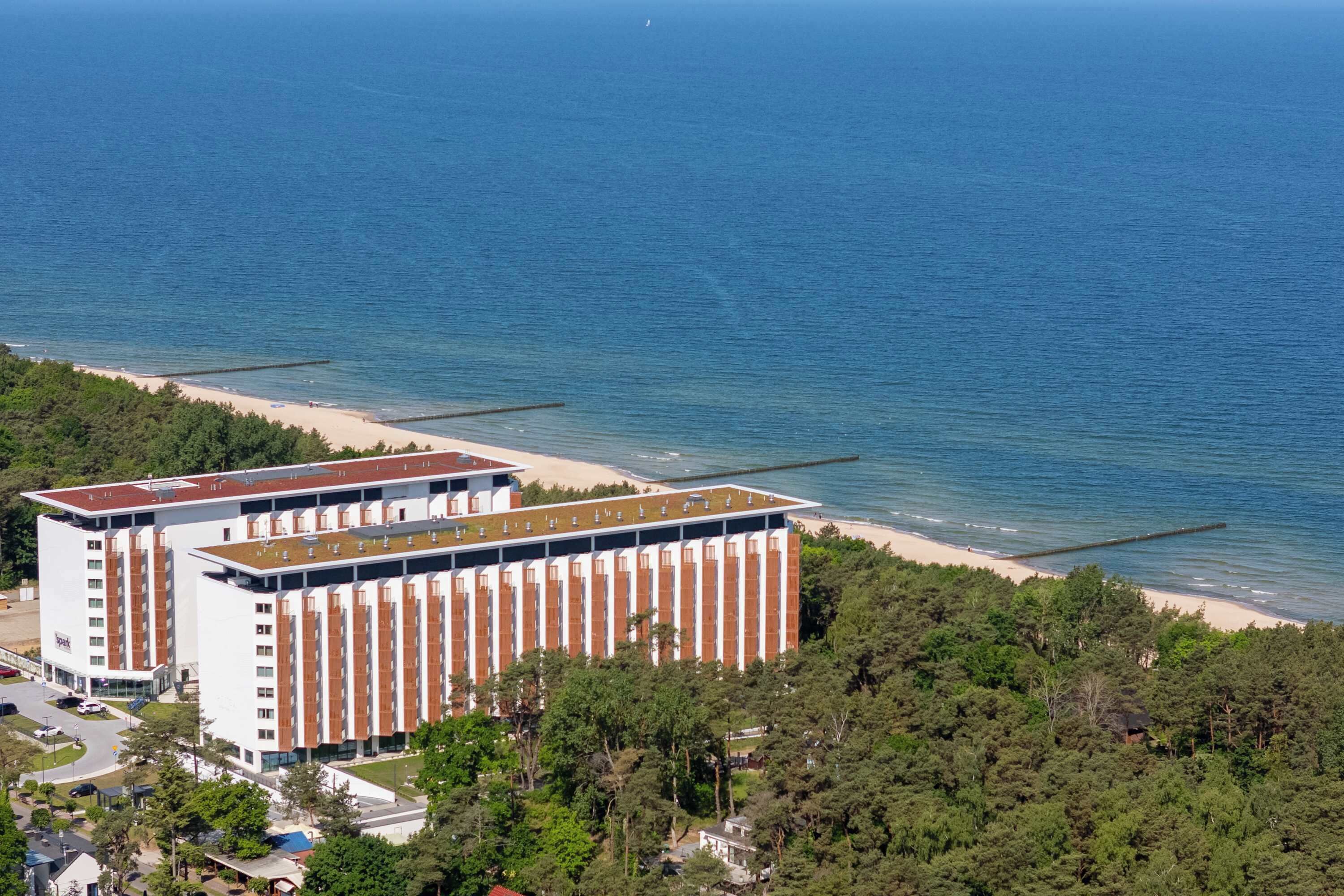 Ein modernes Hotel mit einer flachdachartigen Terrasse mit Blick auf einen Strand und das Meer.