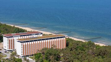 Ein modernes Hotel mit einer flachdachartigen Terrasse mit Blick auf einen Strand und das Meer.