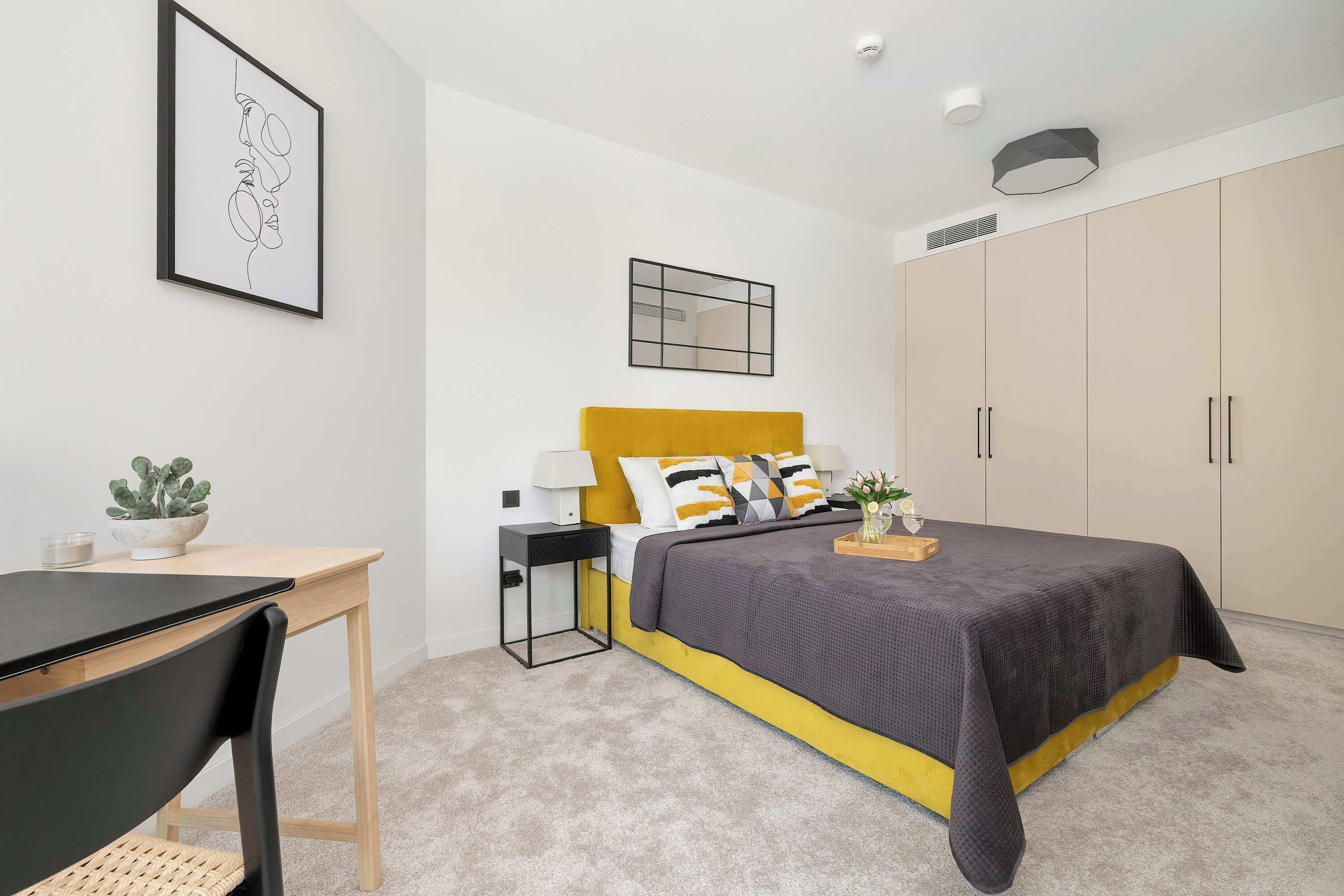 Ein modernes Schlafzimmer mit Bett, Nachttisch, Lampe und großem Kleiderschrank.