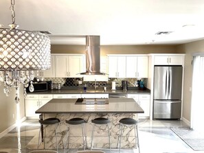 A modern kitchen with a central island, stainless steel appliances, and a decorative chandelier. - Contemporary Resort Home w/ Heated Pool, Old Town (Scottsdale)