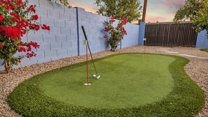 Ein Minigolfplatz mit Puttinggrün, umgeben von einem Kiesweg und einer blauen Wand.
