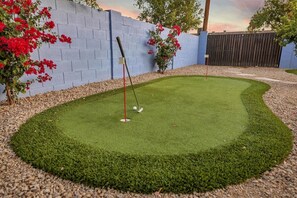A miniature golf course with a putting green, surrounded by a gravel path and a blue wall. - Contemporary Resort Home w/ Heated Pool, Old Town (Scottsdale)