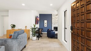 A modern living room with a sofa, a coffee table, a fireplace, and a wooden door. - Elevated Desert Escape | Heated Pool • Putt Green (Scottsdale)