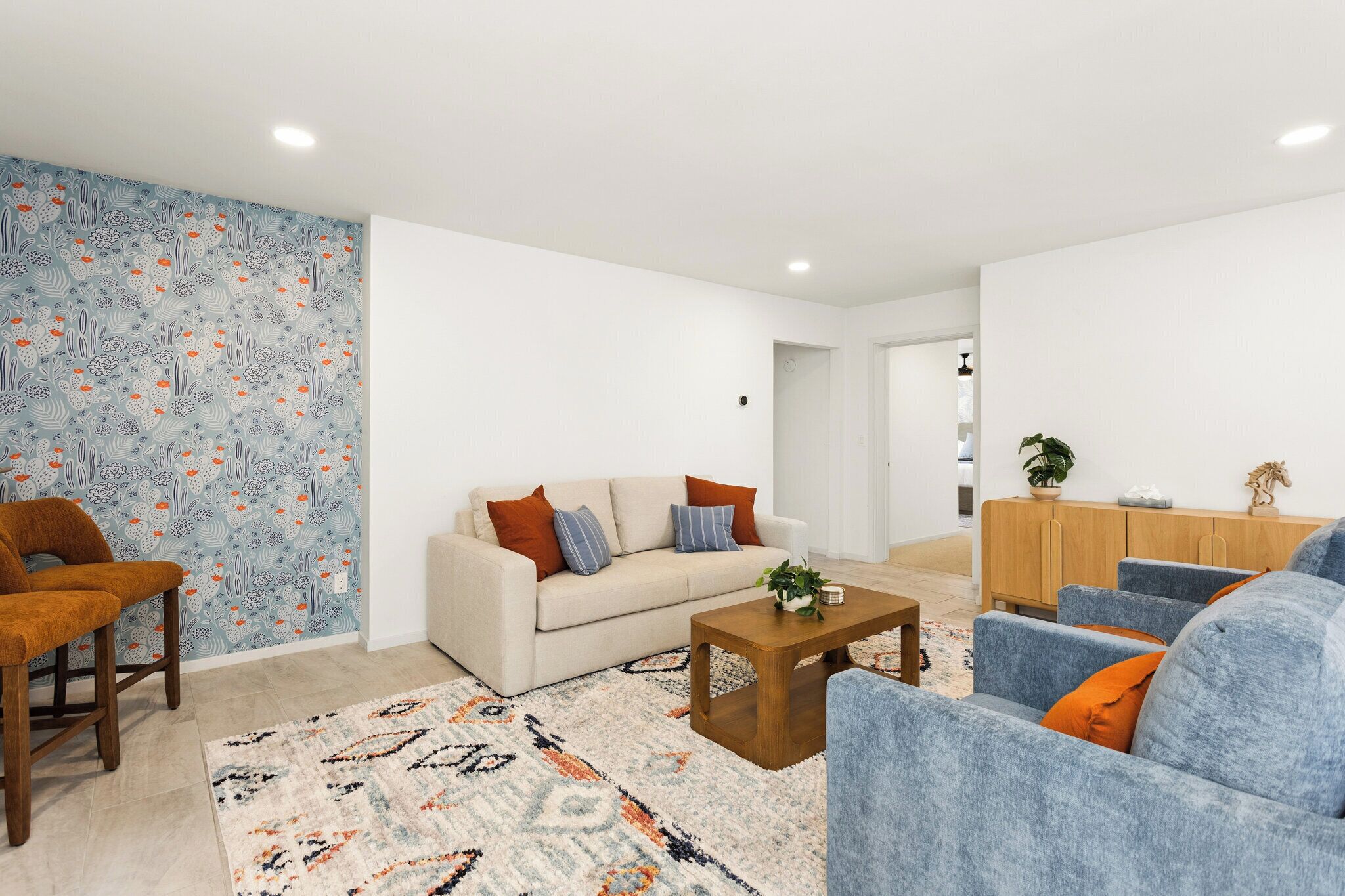 A modern living room with a sofa, armchairs, a coffee table, and a patterned rug.
