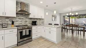 A modern kitchen with white cabinetry, a built-in oven, and a coffee maker. - Elevated Desert Escape | Heated Pool • Putt Green (Scottsdale)
