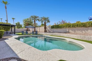 Ein Schwimmbecken mit einer Pergola und Liegestühlen.