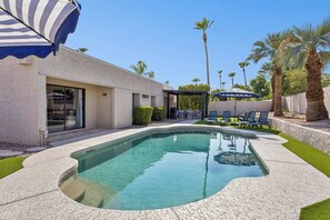 A swimming pool with a patio area, lounge chairs, and a covered seating area. - Elevated Desert Escape | Heated Pool • Putt Green (Scottsdale)