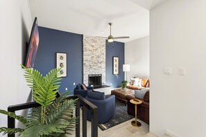 A modern living room with a fireplace, a ceiling fan, and a seating area with a coffee table. - Elevated Desert Escape | Heated Pool • Putt Green (Scottsdale)