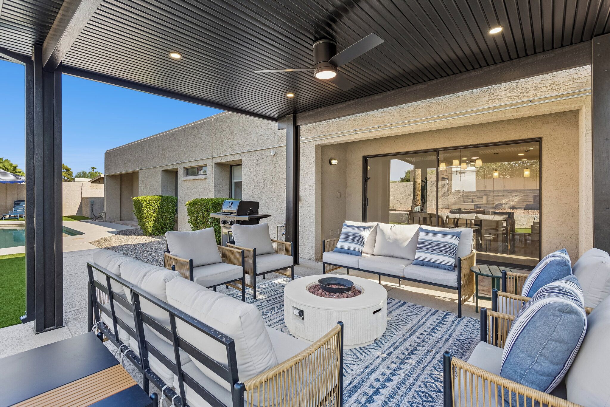 An outdoor patio with a seating area, a grill, and a pool.