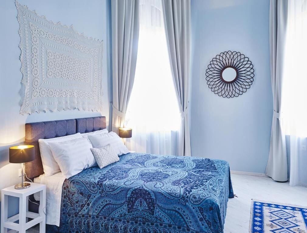Une chambre à coucher avec un lit, des rideaux, un tableau décoratif au mur et une table de chevet.