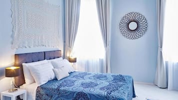 Une chambre à coucher avec un lit, des rideaux, un tableau décoratif au mur et une table de chevet.