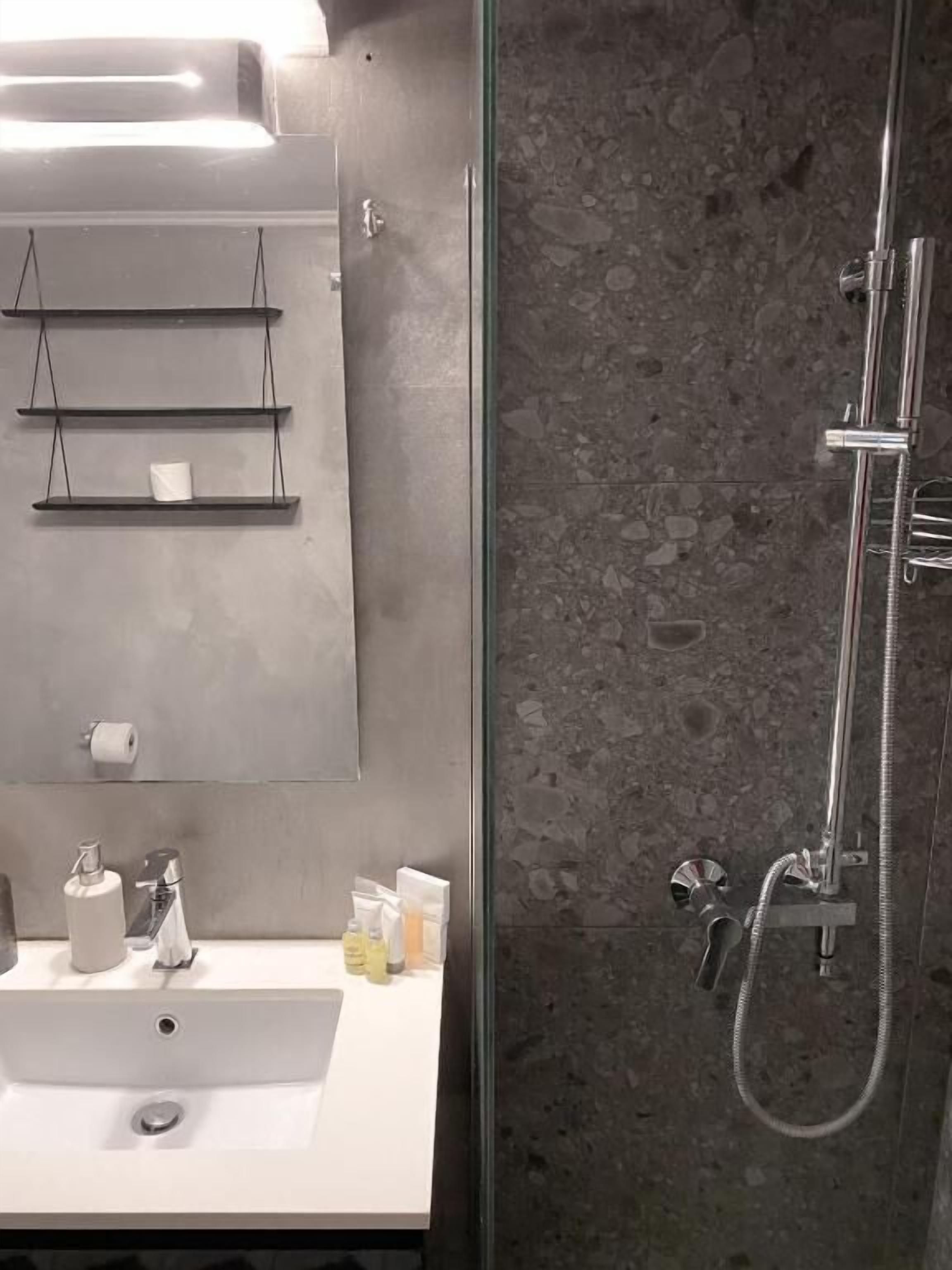 Une salle de bain avec un lavabo blanc, un miroir et une douche.