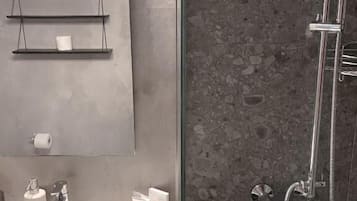 Une salle de bain avec un lavabo blanc, un miroir et une douche.
