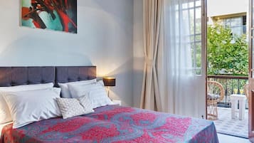 Une chambre à coucher avec un lit, une table de chevet, une lampe et une grande fenêtre avec des rideaux.